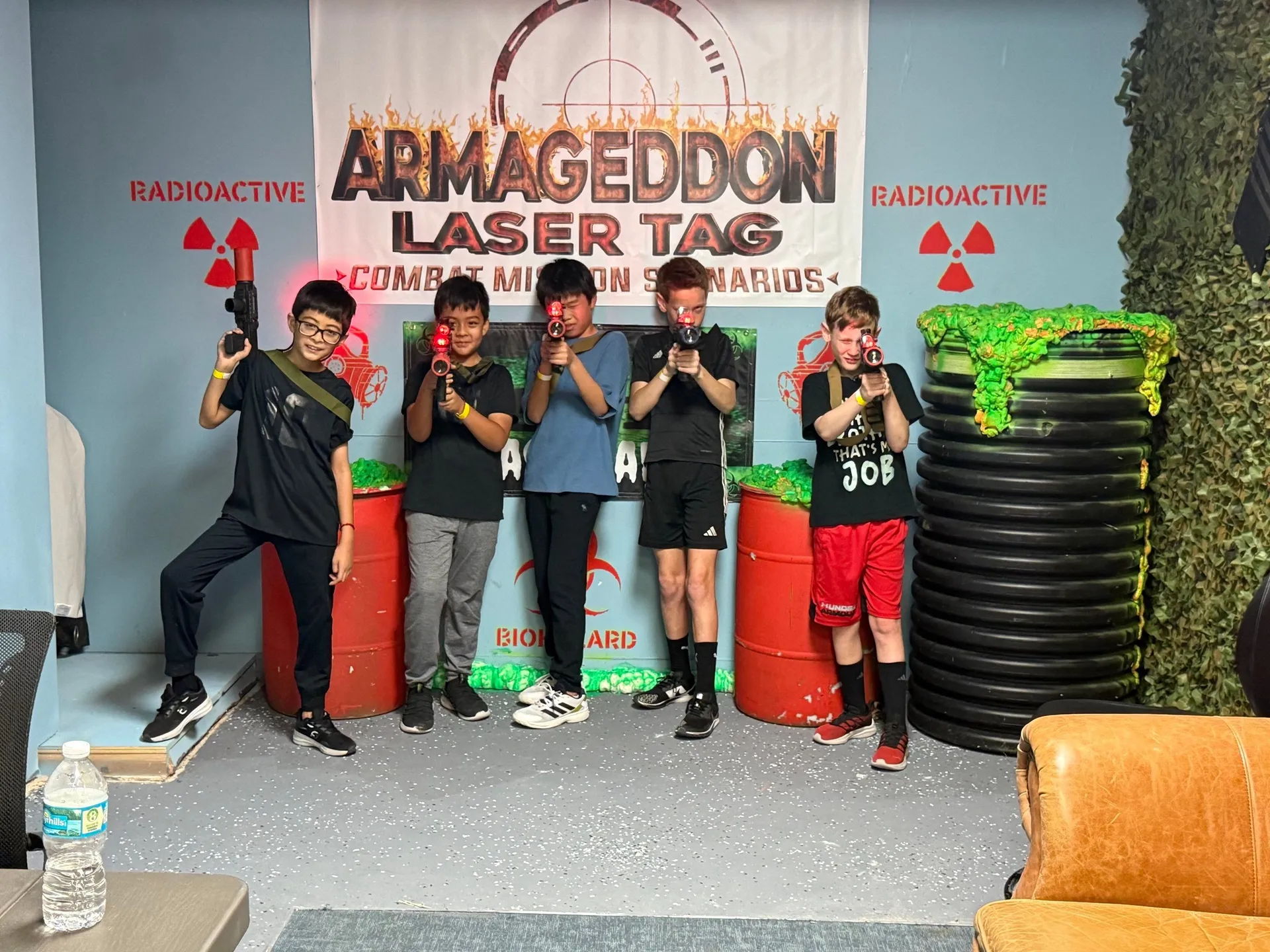 Young players holding tactical laser taggers beneath the Armageddon Laser Tag sign