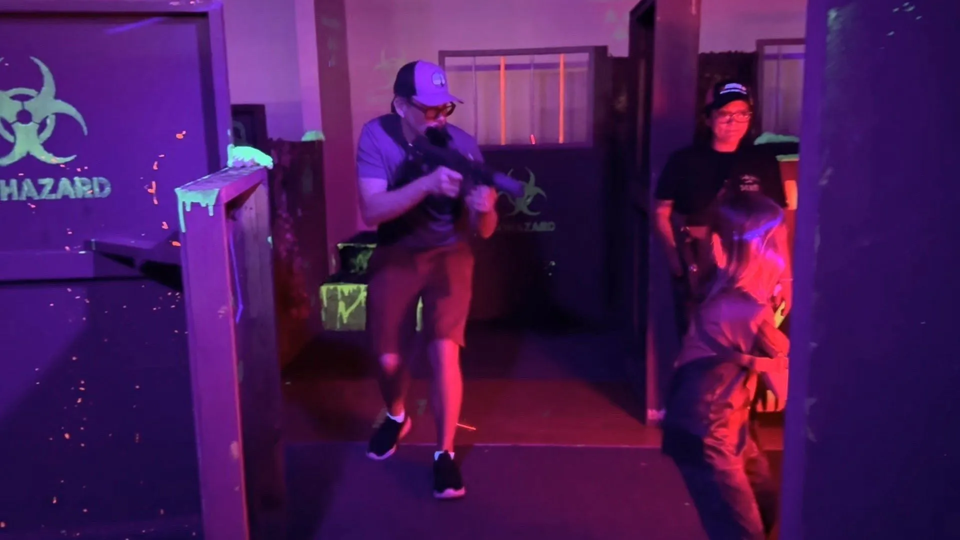 Players moving through a purple-lit tactical laser tag mission